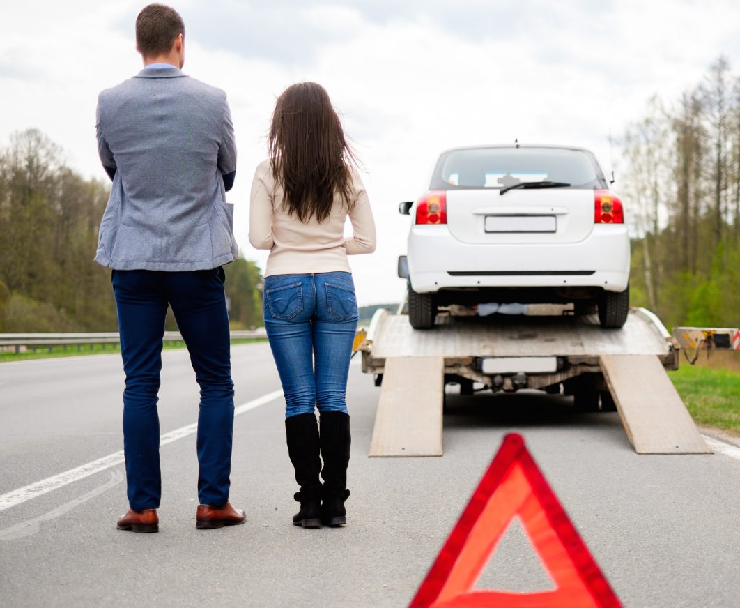 Couple watching their car being loaded onto a flatbed