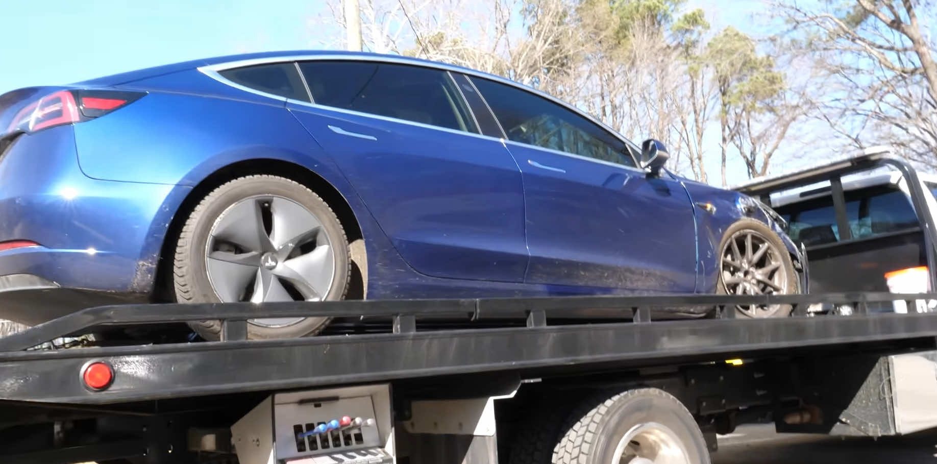 Collision-damaged EV loaded on a flatbed