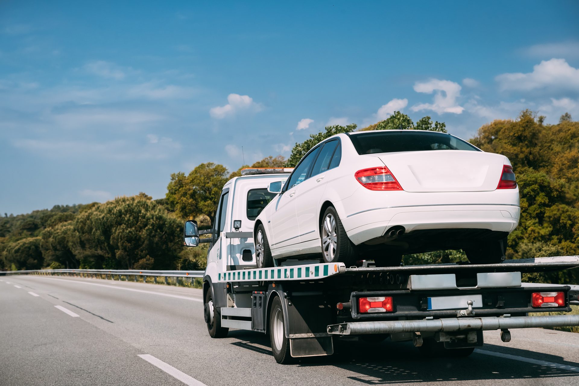 Sedan transported on a flatbed tow truck